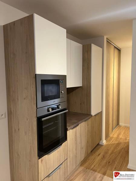 - PRENÁJOM 2-IZ. BYTU S PARKOVACÍM MIESTOM – MILOSLAVOV - Kuchynská časť dvojizbového bytu s podlahou s dreveným dekorom a vstavanými skrinkami.