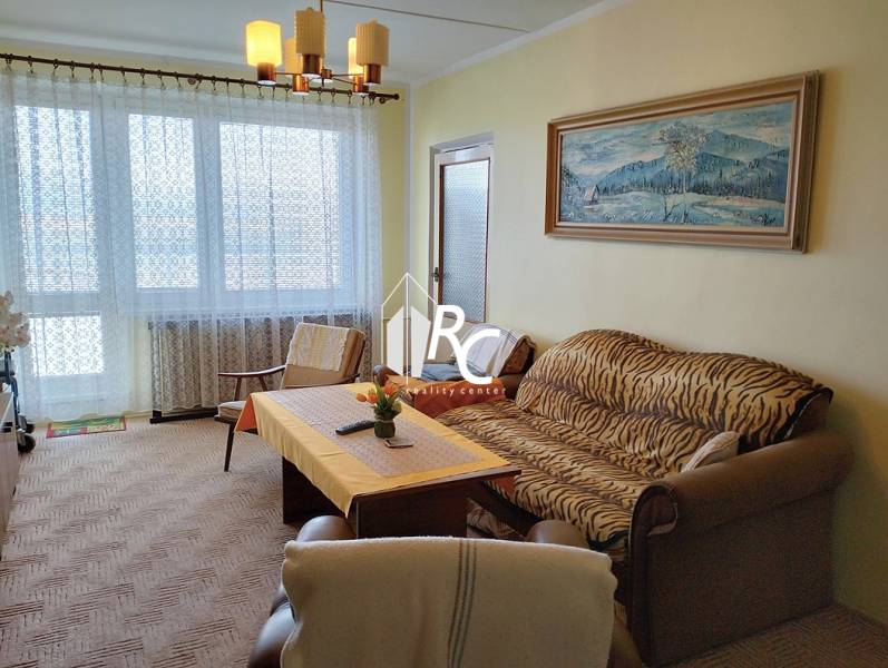 Veľký 2-izbový byt, Martin - Sever - REZERVOVANÉ - Obývacia izba so sedačkou, kreslom a stolom v 2-izbovom byte s veľkým oknom.