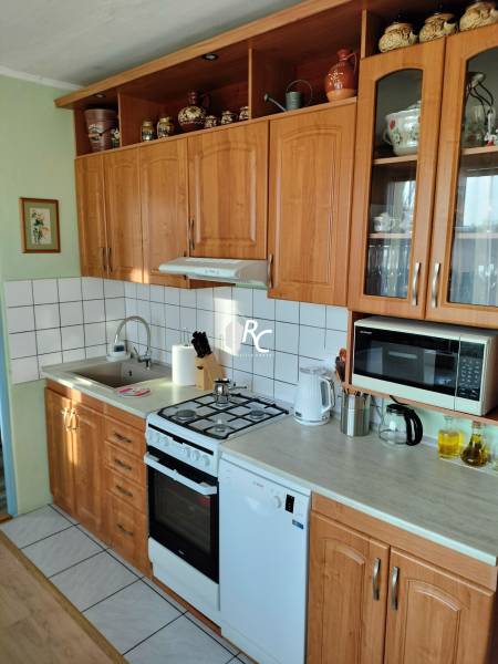 2 izbový byt na Severe - Kuchyňa v 2-izbovom byte s drevenými skrinkami, sporákom a spotrebičmi.