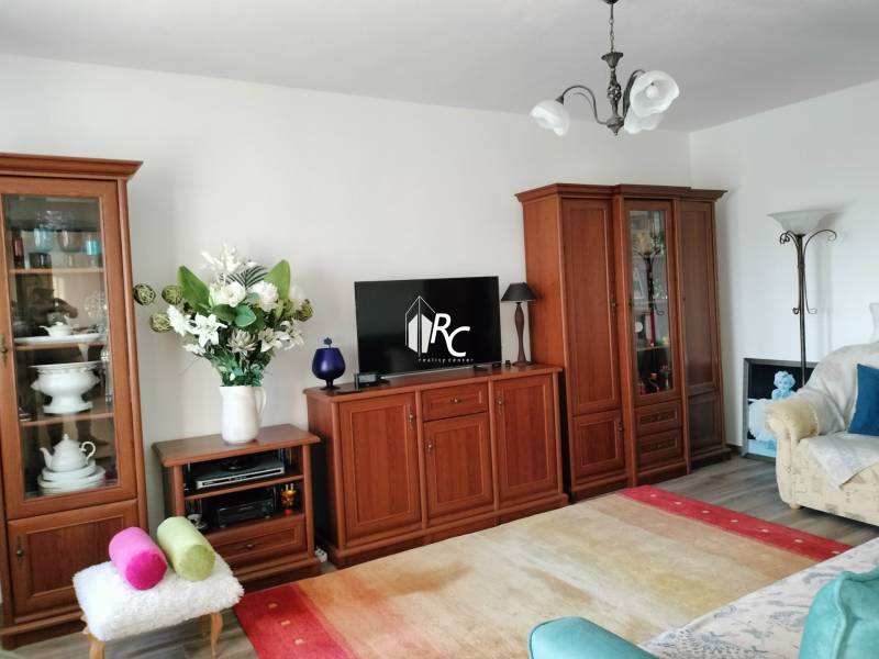 2 izbový byt na Severe - Obývacia izba v 2-izbovom byte s dreveným dekorom a svetlým interiérom.