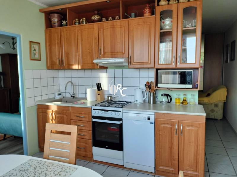 2 izbový byt na Severe - Kuchyňa v 2-izbovom byte s dreveným dekorom, vybavená spotrebičmi a úložným priestorom.