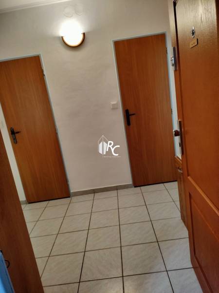 2 izbový byt na Severe - Vstupná chodba v 2-izbovom byte s dlažbou a drevenými dverami.