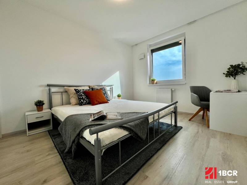 KOMPLETNE ZARIADENÝ SVETLÝ 2-IZB. BYT, NOVOSTAVBA NUPPU, HRANIČNÁ UL. - Spálňa v 2-izbovom byte s podlahou s dreveným dekorom a kovovou posteľou.