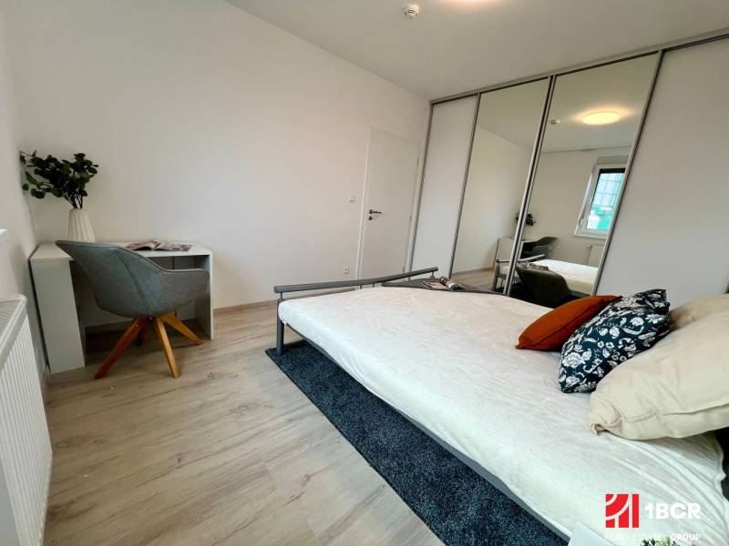 KOMPLETNE ZARIADENÝ SVETLÝ 2-IZB. BYT, NOVOSTAVBA NUPPU, HRANIČNÁ UL. - Spálňa v 2-izbovom byte s posteľou, pracovným stolom a zrkadlovou skriňou.