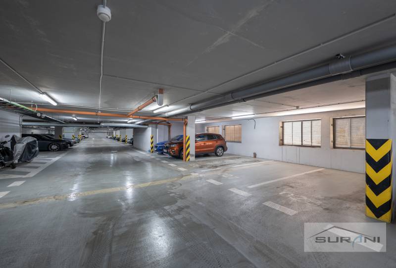 Nové v ponuke | 3-izbový byt 91 m² | 2× balkón | parkovanie | RUSTICA  - Podzemné parkovisko s označenými parkovacími státiami a zaparkovanými autami a motorkami.
