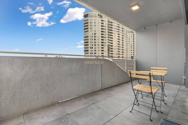 - PREDAJ - APARTMÁN - 38 m2 + 14 m2 LOGGIA - TEHELNÉ POLE - Balkón s moderným nábytkom, výhľad na vysoké budovy v Bratislave - Novom Meste.