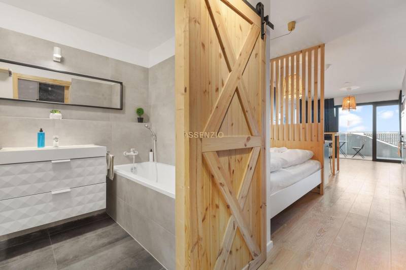 - PREDAJ - APARTMÁN - 38 m2 + 14 m2 LOGGIA - TEHELNÉ POLE - Interiér 1-izbového bytu s vaňou a podlahou s dreveným dekorom.