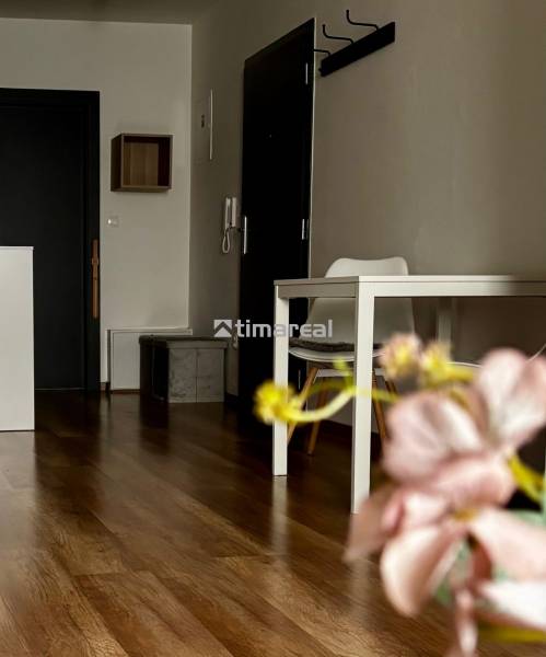 Vkusne zariadený 2i byt na sídlisku WEST,  Galanta - Interiér 2-izbového bytu s podlahou s dreveným dekorom, stolom a kvety v popredí.