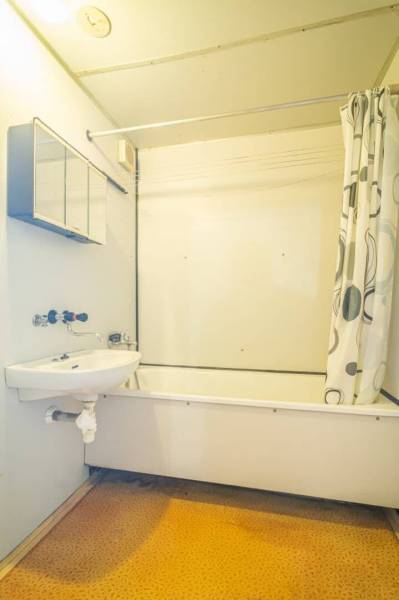 Prenájom 2-izbového bytu v Poprade na Dostojevského ul. - Kúpeľňa s vaňou a sprchovým závesom v 2-izbovom byte, svetlé steny, oranžová podlaha.