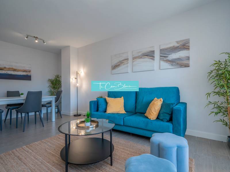 Luxusný byt  Alicante, 112m2, bazén, 2 garáže, posilňovňa - Obývacia izba v 2-izbovom byte s modrou pohovkou a jedálenským stolom.