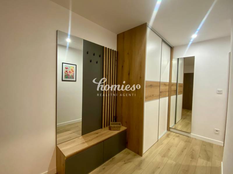 PRENÁJOM luxusný 2 izbový byt v centre mesta Nitra, parkovanie - Interiér 2-izbového bytu s podlahou s dreveným dekorom, vešiakovou stenou a zrkadlom.