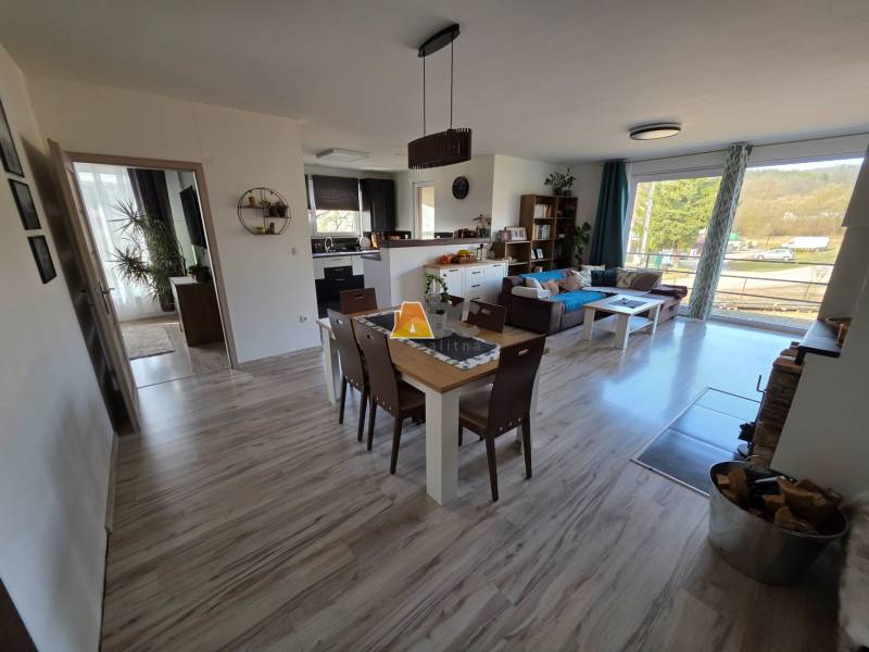 Zabehnutá novostavba: Komfort domu, pokoj vidieka a na skok do BB a ZV - Obývacia izba rodinného domu s otvorenou kuchyňou a podlahou s dreveným dekorom.