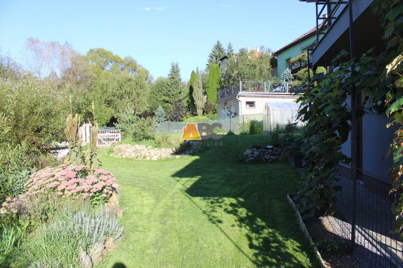 Zabehnutá novostavba: Komfort domu, pokoj vidieka a na skok do BB a ZV - Záhrada pri rodinnom dome na Lipovej ulici v Lukavici, obklopená zeleňou a kvetmi.