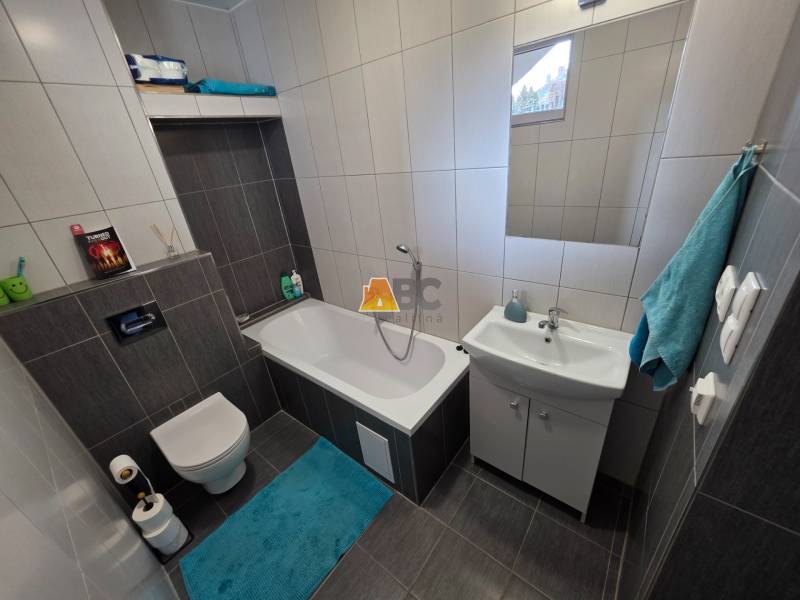 Zabehnutá novostavba: Komfort domu, pokoj vidieka a na skok do BB a ZV - Kúpeľňa v rodinnom dome s vaňou, umývadlom a toaletou, dlažba s tmavým dekorom.