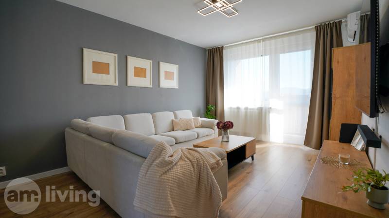 Rezervované -  3i byt v Nemšovej s loggiou po rekonštrukcii - 74m²  - Obývacia izba v 3-izbovom byte so sedačkou a podlahou s dreveným dekorom.