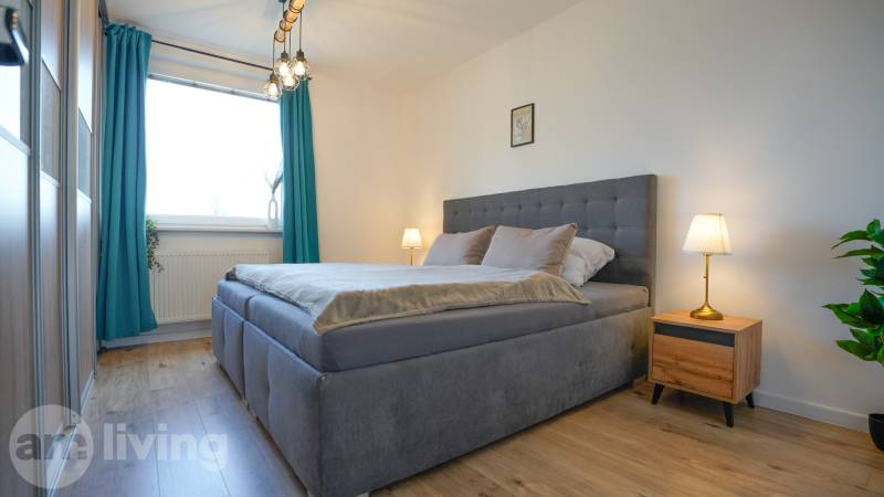 Rezervované -  3i byt v Nemšovej s loggiou po rekonštrukcii - 74m²  - Spálňa v 3-izbovom byte s posteľou, nočnými stolíkmi a podlahou s dreveným dekorom.