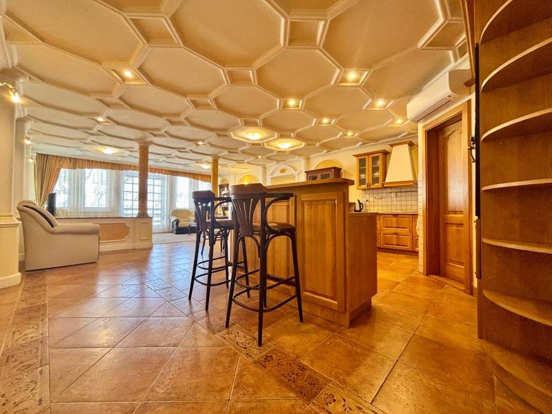 I PRENÁJOM - Priestranný 4 izbový byt na Zámockej ulici, BA - Interiér 4-izbového bytu s ozdobným stropom, podlaha s dreveným dekorom, kuchynským ostrovom a stoličkami.