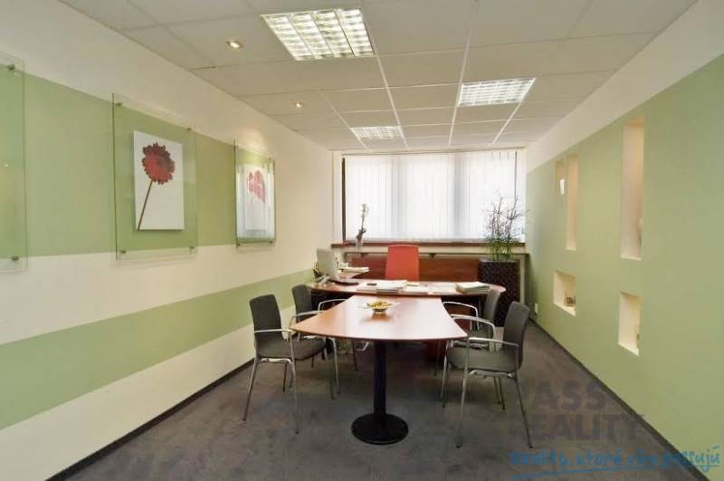 PRENÁJOM kancelárie 27 m2 - Technopol, Kutlíkova ul. - Kancelárie s pracovným stolom, kreslami, umiestnené dekorácie na stenách a okno s vertikálnymi žalúziami.