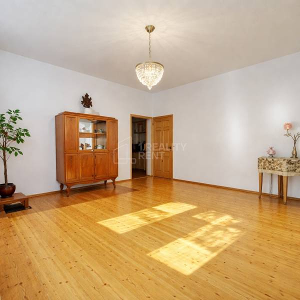 Rodinný dom · Terchová – Biely Potok - Rodinný dom s lustrom, skriňou a podlahou s dreveným dekorom v priestrannej obývačke.