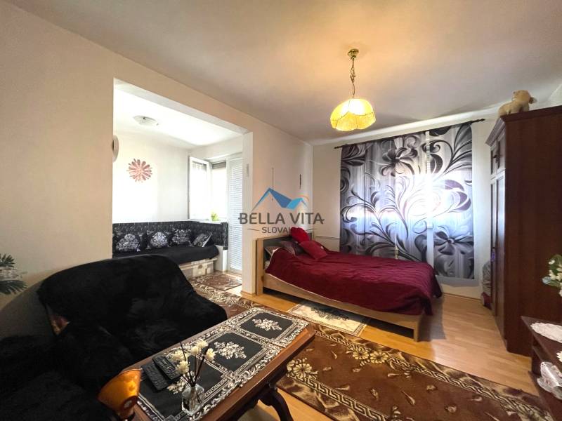 EXKLUZÍVNY PREDAJ - 1 izbový byt, Vodárenská ulica Galanta - Útulný 1-izbový byt s podlahou s dreveným dekorom, posteľou a pohovkou s kvetovaným vzorom.