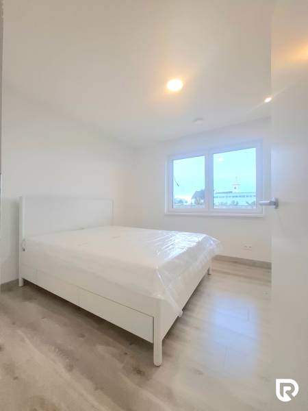 | 4 izbový rodinný dom s krbom a terasov | Slnečná | Ružindol - Spálňa v rodinnom dome s bielou posteľou a podlahou s dreveným dekorom.