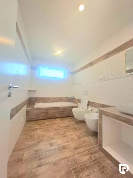 | 4 izbový rodinný dom s krbom a terasov | Slnečná | Ružindol - Kúpeľňa v rodinnom dome s vaňou a toaletou, podlaha s dreveným dekorom.