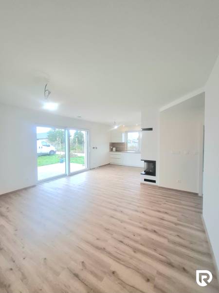 | 4 izbový rodinný dom s krbom a terasov | Slnečná | Ružindol - Obývacia izba v Rodinnom dome s podlahou s dreveným dekorom a priehľadmi do záhrady.