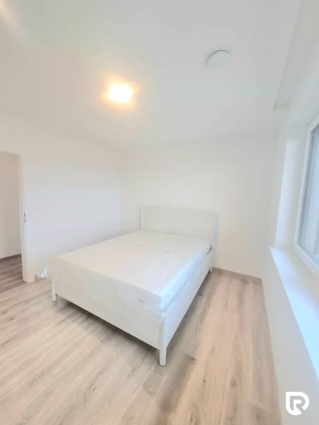 | 4 izbový rodinný dom s krbom a terasov | Slnečná | Ružindol - Spálňa v rodinnom dome s posteľou, bielymi stenami a podlahou s dreveným dekorom.