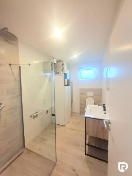 | 4 izbový rodinný dom s krbom a terasov | Slnečná | Ružindol - Kúpeľňa v rodinnom dome s podlahou s dreveným dekorom a sprchovacím kútom.