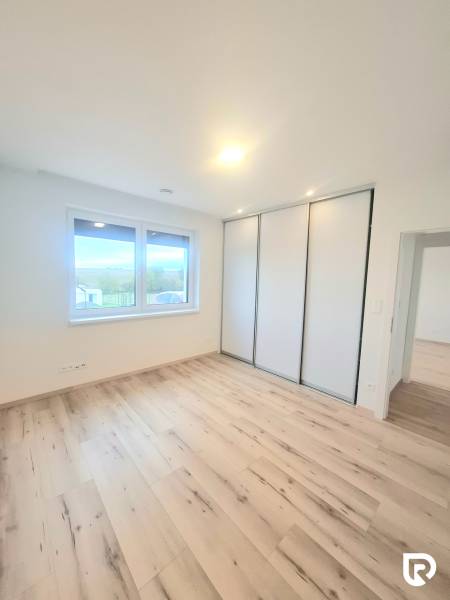 | 4 izbový rodinný dom s krbom a terasov | Slnečná | Ružindol - Miestnosť v rodinnom dome s podlahou s dreveným dekorom, šatníkovou skriňou a oknom.