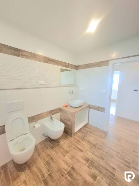 | 4 izbový rodinný dom s krbom a terasov | Slnečná | Ružindol - Kúpeľňa v rodinnom dome s toaletou a bidetom, obklopuje ju podlaha s dreveným dekorom.