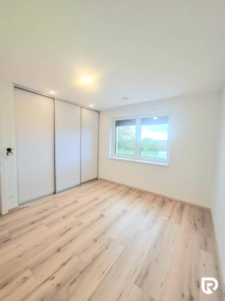 | 4 izbový rodinný dom s krbom a terasov | Slnečná | Ružindol - Izba s podlahou s dreveným dekorom a vstavanou skriňou v rodinnom dome.