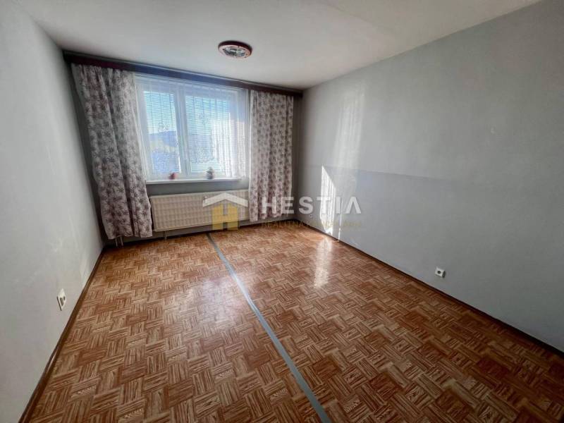 NOVINKA 3 izbový byt v Brezovej pod Bradlom s krásnym výhľadom - Izba v 3-izbovom byte s podlahou s dreveným dekorom a svetlom šedými stenami.