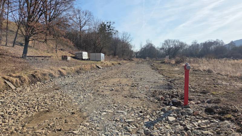 NA PREDAJ STAVEBNÝ POZEMOK  V DOSAHU MHD PREŠOV - HANISKA - Pozemky - bývanie v Haniske, kamenistá cesta medzi stromami a kontajner.