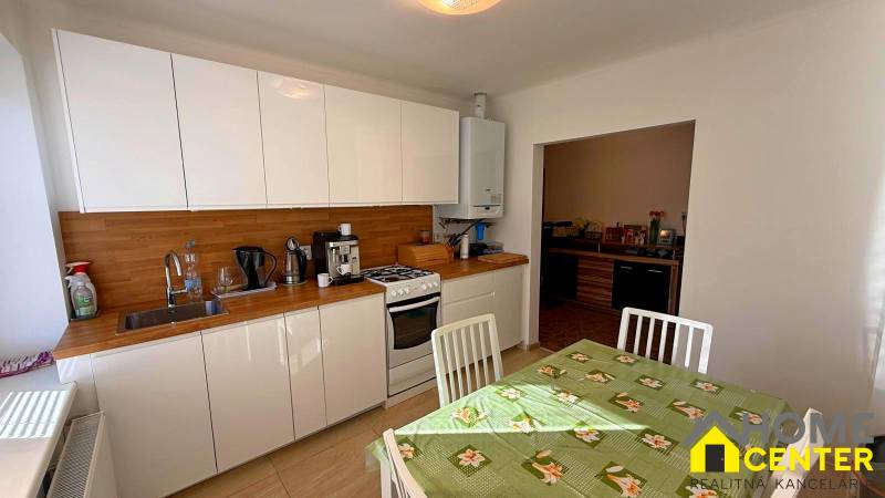 ZĽAVA!! NA PREDAJ RODINNÝ DOM V ZEMIANSKEJ OLČI – PO REKONŠTRUKCII - Kuchyňa v rodinnom dome s bielymi skrinkami, dreveným dekorom a jedálenským stolom.