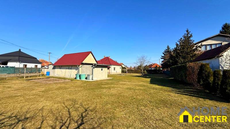 ZĽAVA!! NA PREDAJ RODINNÝ DOM V ZEMIANSKEJ OLČI – PO REKONŠTRUKCII - Trávnatý pozemok pri rodinnom dome v Zemianskej Olči s niekoľkými domami a kríkmi.