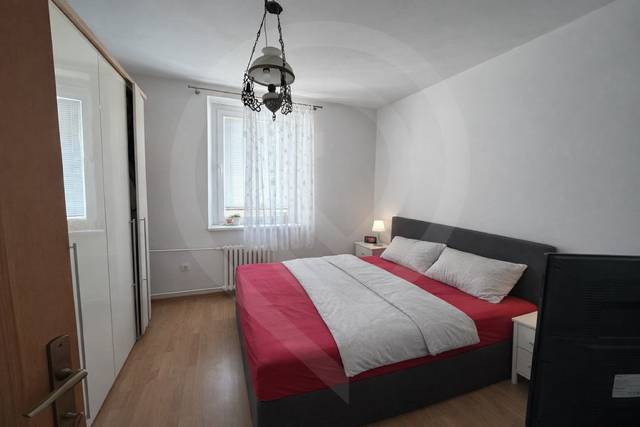 Predaj 3.izbového bytu v Ružinove v obkolesené borovicového lesíka - Spálňa s posteľou a skrinkou, podlaha s dreveným dekorom, 3-izbový byt.