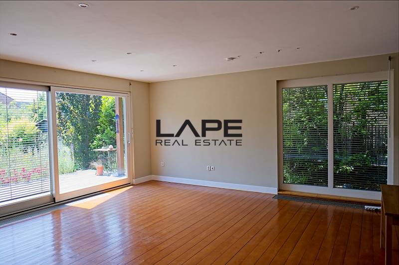 Rodinný dom s veľkou záhradou - Ružinov  - Obývačka s veľkými oknami a podlahou s dreveným dekorom v rodinnom dome.