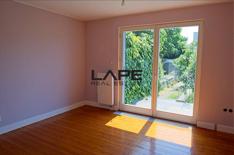 Rodinný dom s veľkou záhradou - Ružinov  - Izba v rodinnom dome s podlahou s dreveným dekorom a výhľadom na záhradu.