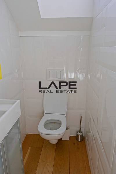 Rodinný dom s veľkou záhradou - Ružinov  - Kúpeľňa v rodinnom dome s podlahou s dreveným dekorom a bielymi stenami.