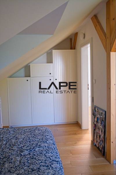 Rodinný dom s veľkou záhradou - Ružinov  - Spálňa v rodinnom dome s podlahou s dreveným dekorom a vstavanými skriňami pod šikmým stropom.