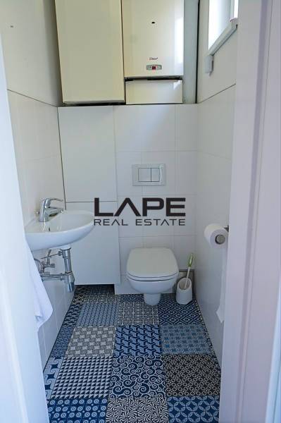 Rodinný dom s veľkou záhradou - Ružinov  - Toaleta s farebnou dlažbou v Rodinnom dome, biely obklad a malé umývadlo.