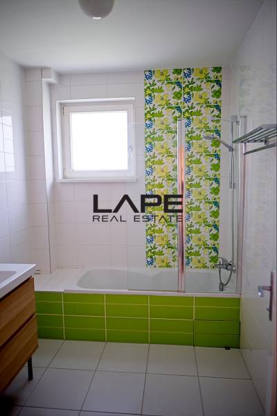 Rodinný dom s veľkou záhradou - Ružinov  - Kúpeľňa v rodinnom dome s vaňou, farebnými obkladmi a oknom pre prirodzené svetlo.