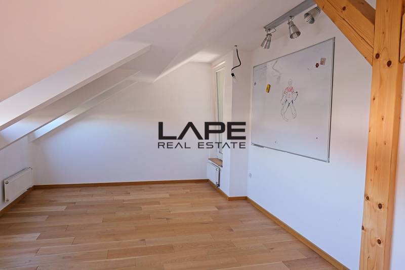 Rodinný dom s veľkou záhradou - Ružinov  - Podkrovná miestnosť s bielou tabuľou a podlahou s dreveným dekorom v rodinnom dome.