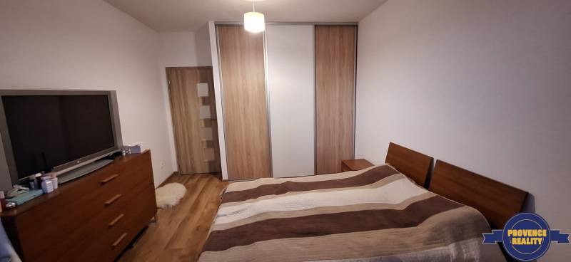 PREDAJ: 4 izbový byt s balkónom, 82 m2 - KOMÁRNO - Spálňa v 4-izbovom byte s podlahou s dreveným dekorom a veľkou skriňou.