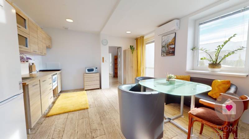 DOBROHOŠŤ- Prenájom  3i zariadeného bytu s predzáhradkou a parkingom - Kuchyňa v 3-izbovom byte s podlahou s dreveným dekorom, svetlými skrinkami a jedálenským stolom.