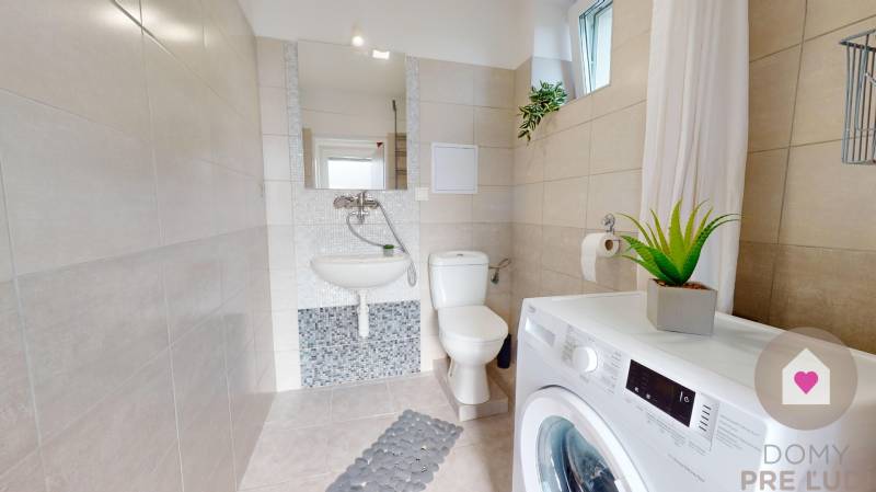 DOBROHOŠŤ- Prenájom  3i zariadeného bytu s predzáhradkou a parkingom - Kúpeľňa v 3-izbovom byte s práčkou, toaletou, umývadlom a rastlinou. Biele obklady.