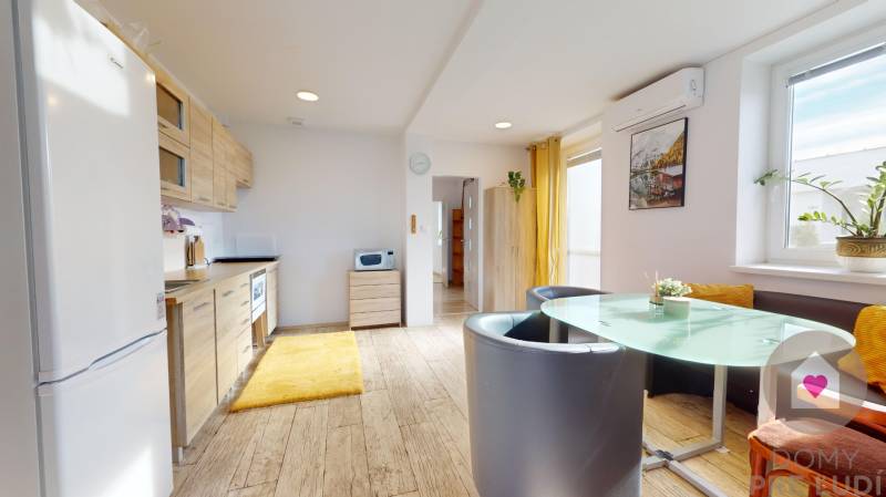 DOBROHOŠŤ- Prenájom  3i zariadeného bytu s predzáhradkou a parkingom - Kuchyňa v 3-izbovom byte s podlahou s dreveným dekorom a jedálenským stolom.