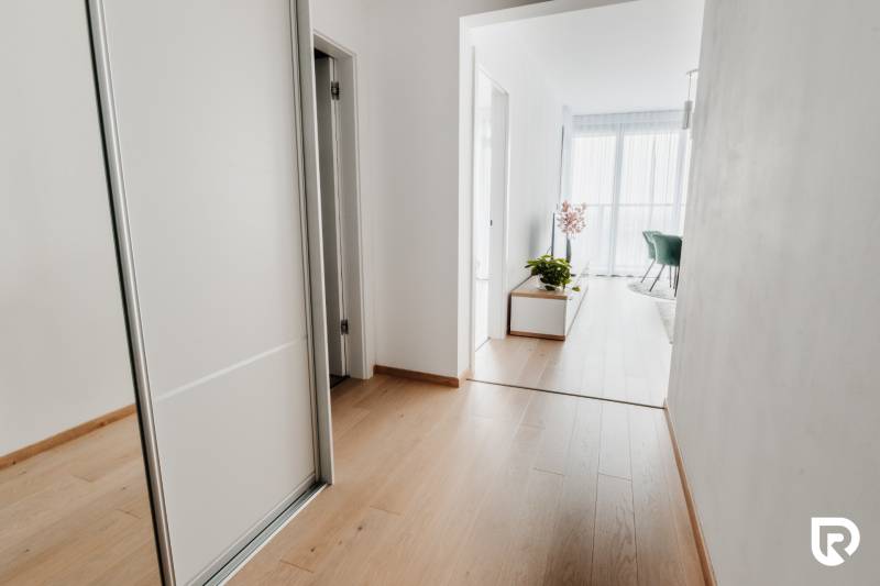 | E2Tower | 20.poschodie | 2i byt | panoramatický výhľad |  - Chodba v 2-izbovom byte s podlahou s dreveným dekorom a bielymi stenami.