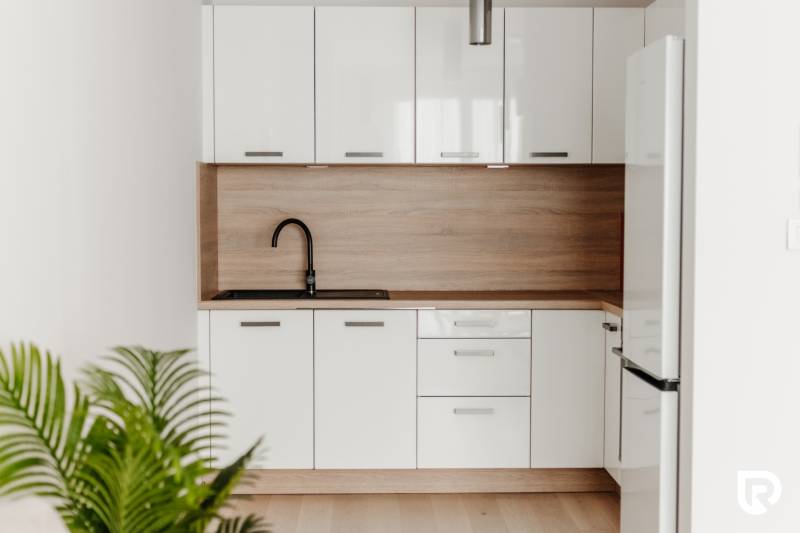 | E2Tower | 20.poschodie | 2i byt | panoramatický výhľad |  - Kuchynská linka s bielymi skrinkami a podlahou s dreveným dekorom, 2-izbový byt.